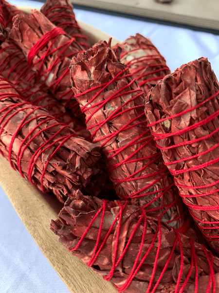 Hand-tied Dragon's Blood Sage bundles with vibrant red threads, ready to cleanse and protect with their potent, ethically sourced smoke.